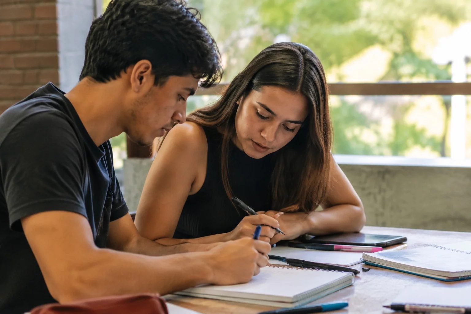 Dois estudantes preparando um debate com cadernos e marcadores